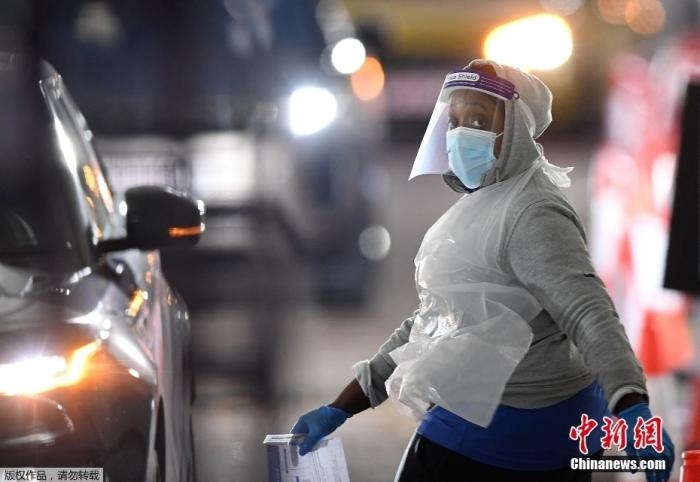 當(dāng)?shù)貢r(shí)間12月18日，英國(guó)政府公布的數(shù)據(jù)顯示，當(dāng)天英國(guó)新增奧密克戎毒株感染病例10059例。鑒于奧密克戎毒株感染病例激增，住院人數(shù)不斷上升，倫敦市長(zhǎng)宣布倫敦進(jìn)入“重大事故”狀態(tài)。圖為倫敦的一個(gè)免下車檢測(cè)中心，一名醫(yī)務(wù)工作者正準(zhǔn)備對(duì)司機(jī)進(jìn)行核酸檢測(cè)。