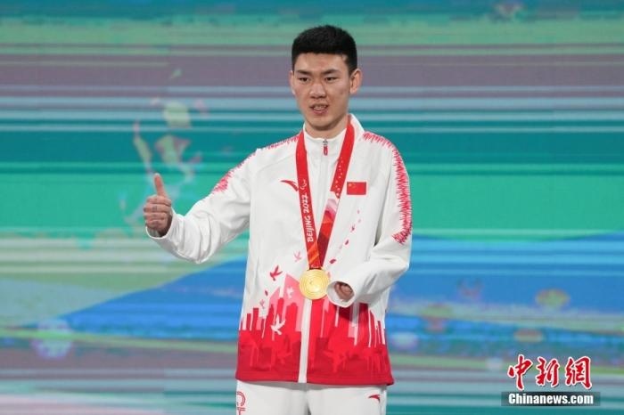 3月6日，梁景怡在延慶頒獎廣場領獎臺上豎起大拇指。當日，在國家高山滑雪中心舉行的北京2022年冬殘奧會殘奧高山滑雪男子超級大回轉(zhuǎn)—站姿決賽中，中國選手梁景怡奪得冠軍。 <a target='_blank' href='/'>中新社</a>記者 楊華峰 攝