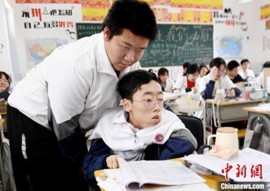 朱金祥(左)把鐘華強(qiáng)放到課堂座位上后，都要把他擺正好，確認(rèn)安全后才回到自己的座位上。 卓忠偉 攝