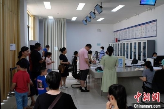 圖為在戶籍辦證廳內(nèi)排隊(duì)等待的家長和孩子。劉俊聰 攝