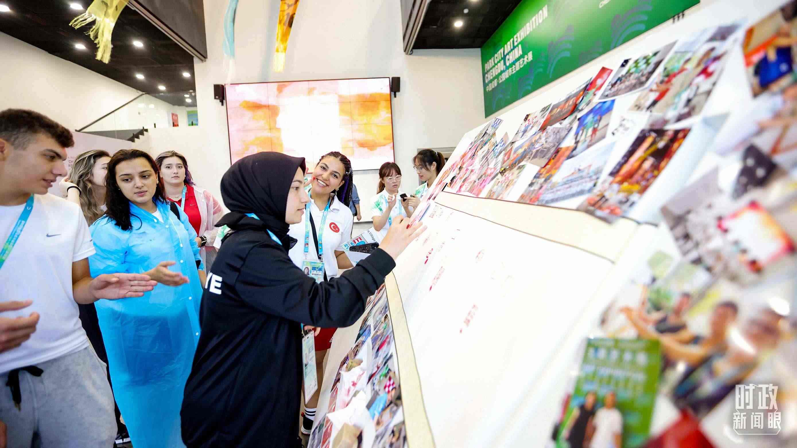 各國青年運(yùn)動(dòng)員正在參觀成都大運(yùn)村內(nèi)的“雪山下的公園城市，煙火里的幸福成都”主題藝術(shù)展。（總臺(tái)央視記者魏幫軍拍攝）