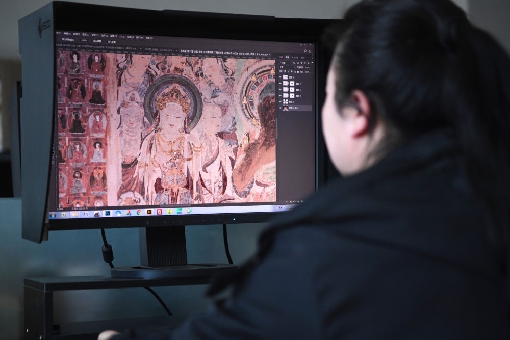 敦煌研究院文物數(shù)字化保護(hù)團(tuán)隊(duì)圖像處理人員年海麗在拼接壁畫圖像（2023年4月25日攝）。數(shù)字化探索為莫高窟的保護(hù)與傳承開辟了全新路徑，數(shù)字技術(shù)讓敦煌文物走出洞窟，跨出國(guó)門，走向“永久保存、永續(xù)利用”。新華社記者 陳斌 攝
