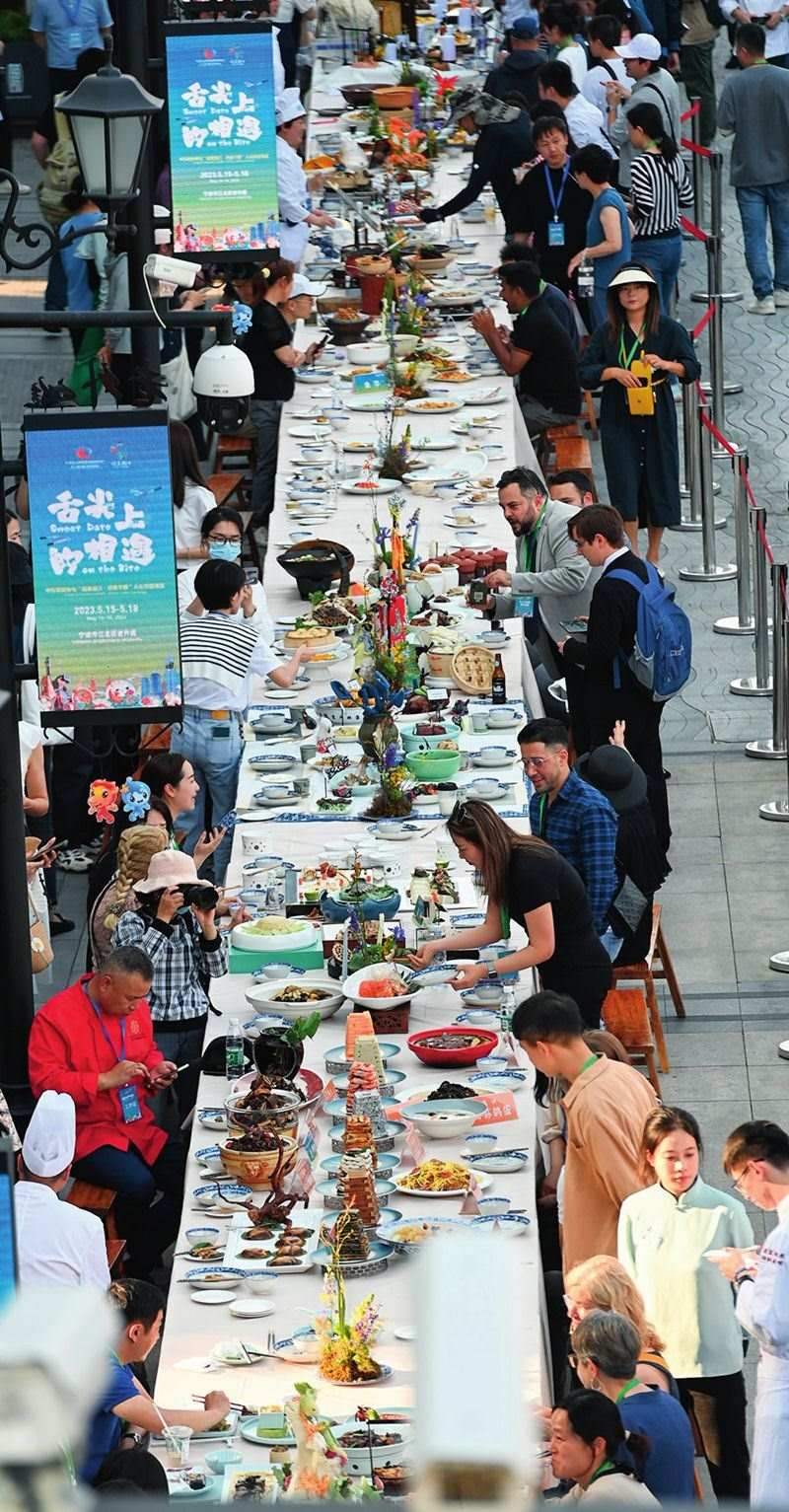 市民和游客在寧波舉辦的第三屆中國(guó)—中東歐國(guó)家博覽會(huì)暨國(guó)際消費(fèi)品博覽會(huì)上品嘗融合中國(guó)和中東歐美食的長(zhǎng)桌宴（2023年5月15日攝）。黃宗治攝/本刊