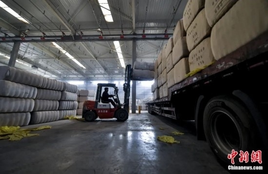 新疆喀什綜合保稅區(qū)，喀什啟路國際貿(mào)易有限公司的倉庫內(nèi)，工人正在裝載從塔吉克斯坦和烏茲別克斯坦進(jìn)口的棉花。劉新攝