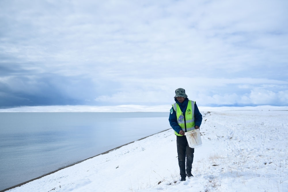 2021年10月20日，在青海省果洛藏族自治州瑪多縣扎陵湖鄉(xiāng)勒那村，三江源國家公園黃河源園區(qū)生態(tài)管護員在扎陵湖邊撿拾垃圾。新華社記者 張龍 攝