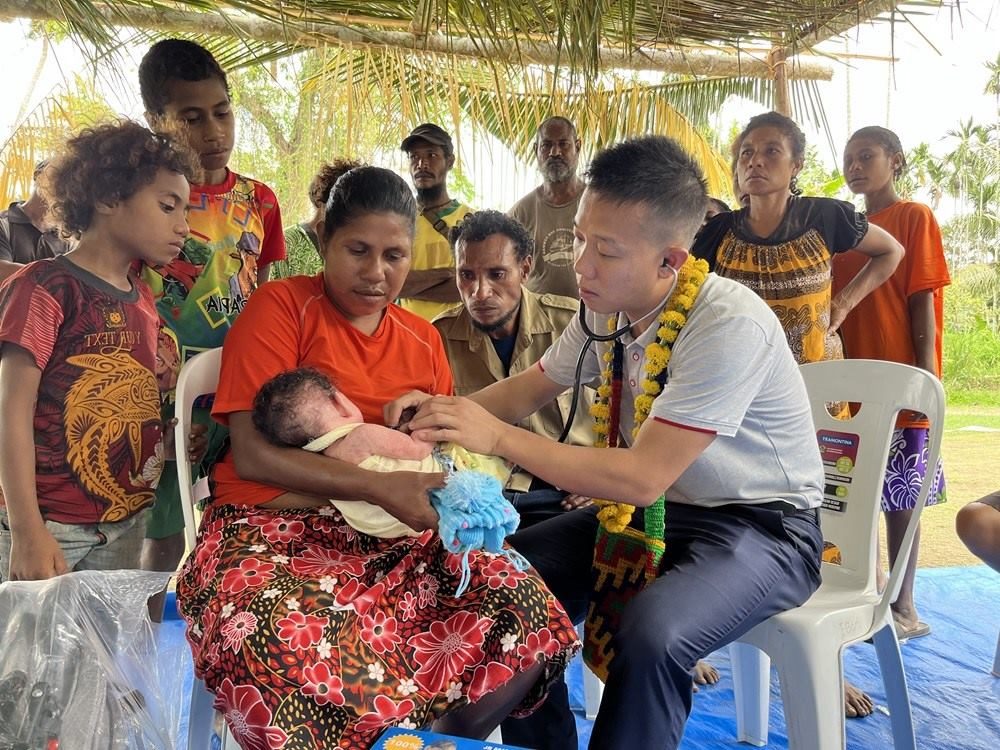 2023年8月5日，在巴布亞新幾內(nèi)亞中央省的一個(gè)村莊里，第12批援巴新中國(guó)醫(yī)療隊(duì)副隊(duì)長(zhǎng)、新生兒科副主任醫(yī)師劉振球?yàn)楫?dāng)?shù)貗雰郝?tīng)診檢查。新華社發(fā)（第12批援巴新中國(guó)醫(yī)療隊(duì)供圖）