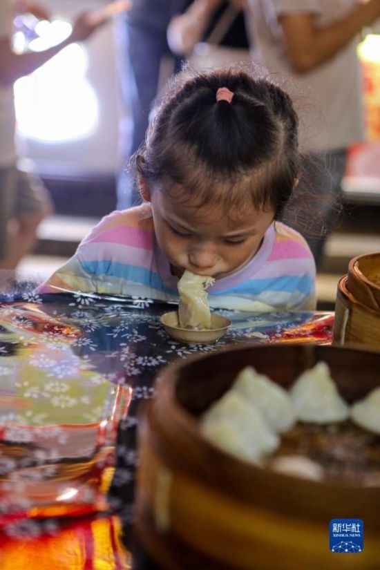 9月27日，小朋友在南翔小籠長(zhǎng)街宴上品嘗南翔小籠。