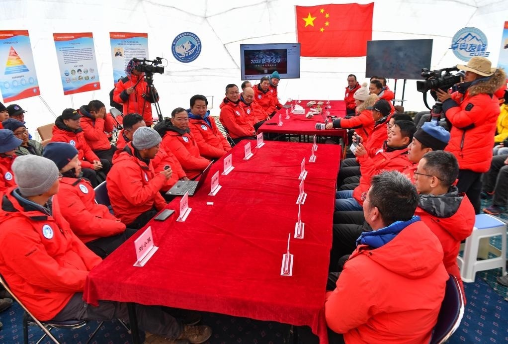 海拔4950米的卓奧友峰科考大本營，科考隊員趙華標(biāo)（手拿麥克風(fēng)看電腦者）在宣讀剛剛接收到的頂峰氣象觀測數(shù)據(jù)，這標(biāo)志著峰頂自動氣象站架設(shè)成功，成功傳回觀測數(shù)據(jù)（10月1日攝）。新華社記者晉美多吉 攝