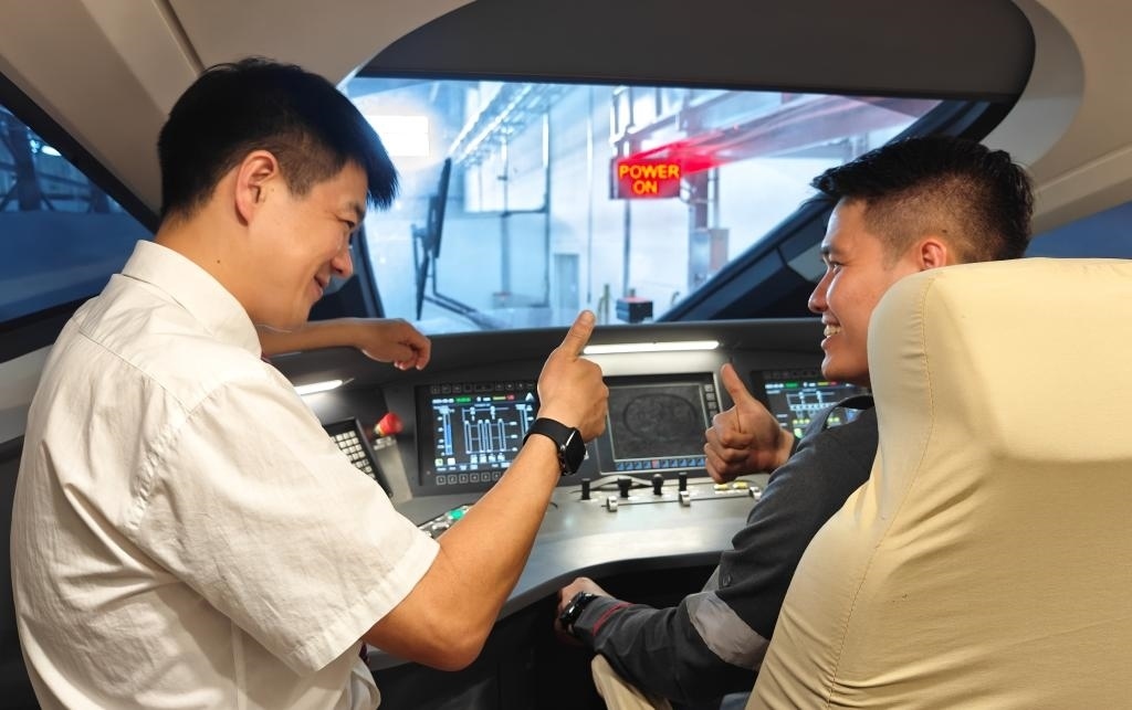 8月25日，在印度尼西亞萬隆的雅萬高鐵德卡魯爾動車所內(nèi)，中國師傅穆振（左）在向印尼火車司機塞蒂亞萬講解動車組出庫前的上電作業(yè)。