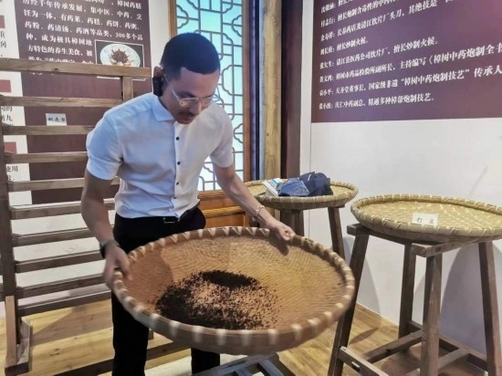 2023“一帶一路”媒體合作論壇聯(lián)合采訪團團員在非遺文化展示館體驗中藥炮制技藝。（本報記者 黃超攝）