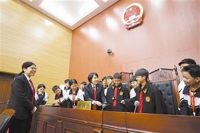 圖③：同學們穿法袍、敲法槌，爭做“小法官”。