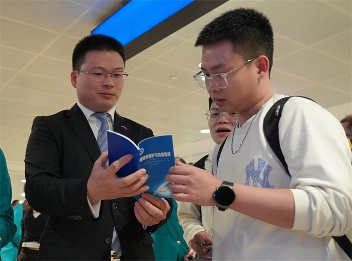 工作人員（左一）在發(fā)放《中國領(lǐng)事保護與協(xié)助指南》。 中國駐迪拜總領(lǐng)事館供圖