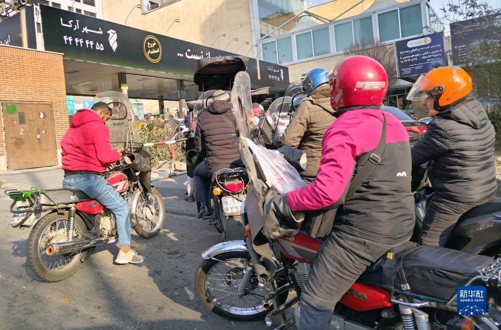 12月18日，摩托車在伊朗首都德黑蘭的一家加油站外等待加油。新華社記者 沙達提 攝