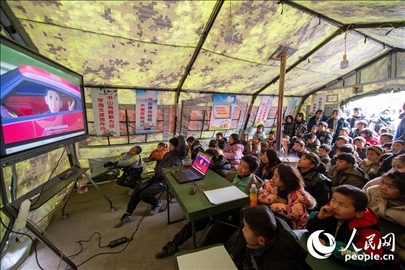 12月22日，在積石山縣大河家鎮(zhèn)大河村安置點(diǎn)，陸軍76集團(tuán)軍某旅搭建的“臨時(shí)學(xué)?！眱?nèi)，小朋友正在看動(dòng)畫片。人民網(wǎng)記者 翁奇羽攝