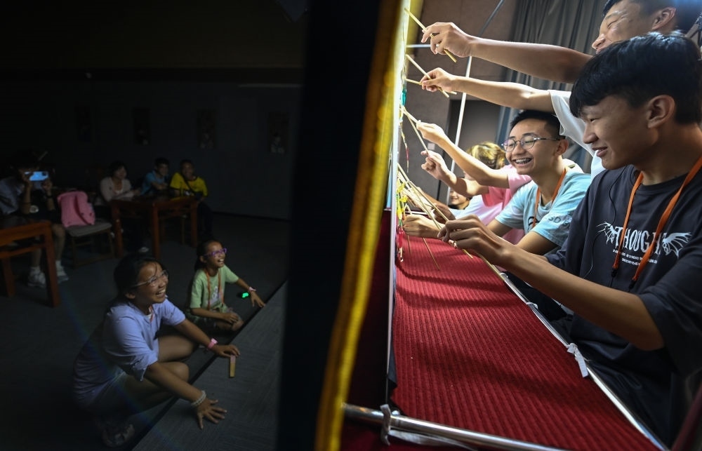 2023年8月8日，進(jìn)行暑期研學(xué)的學(xué)生在位于陜西省西安市的中國秦腔藝術(shù)博物館體驗皮影戲演出。新華社記者 鄒競一 攝