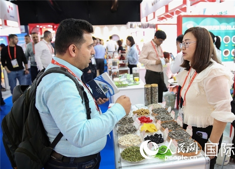 圖為一家中國(guó)干果參展企業(yè)代表與采購(gòu)商洽談。人民網(wǎng) 塔里克·易卜拉欣攝