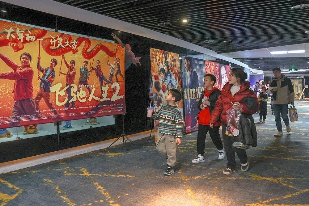 △ 2024年2月16日，在江西贛州一家電影院，觀眾從春節(jié)檔電影的宣傳展板前走過。