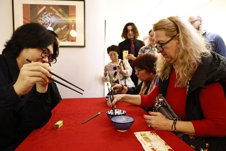 羅馬尼亞觀眾體驗(yàn)用筷子夾花生。中國(guó)文化中心供圖