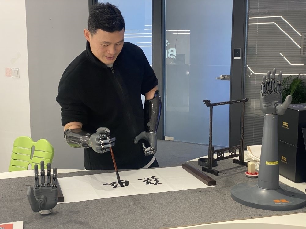 2024年3月29日，在浙江強腦科技有限公司展廳內，失去雙手的產品體驗官倪敏成依靠智能仿生手寫毛筆字。新華社記者 魏一駿 攝