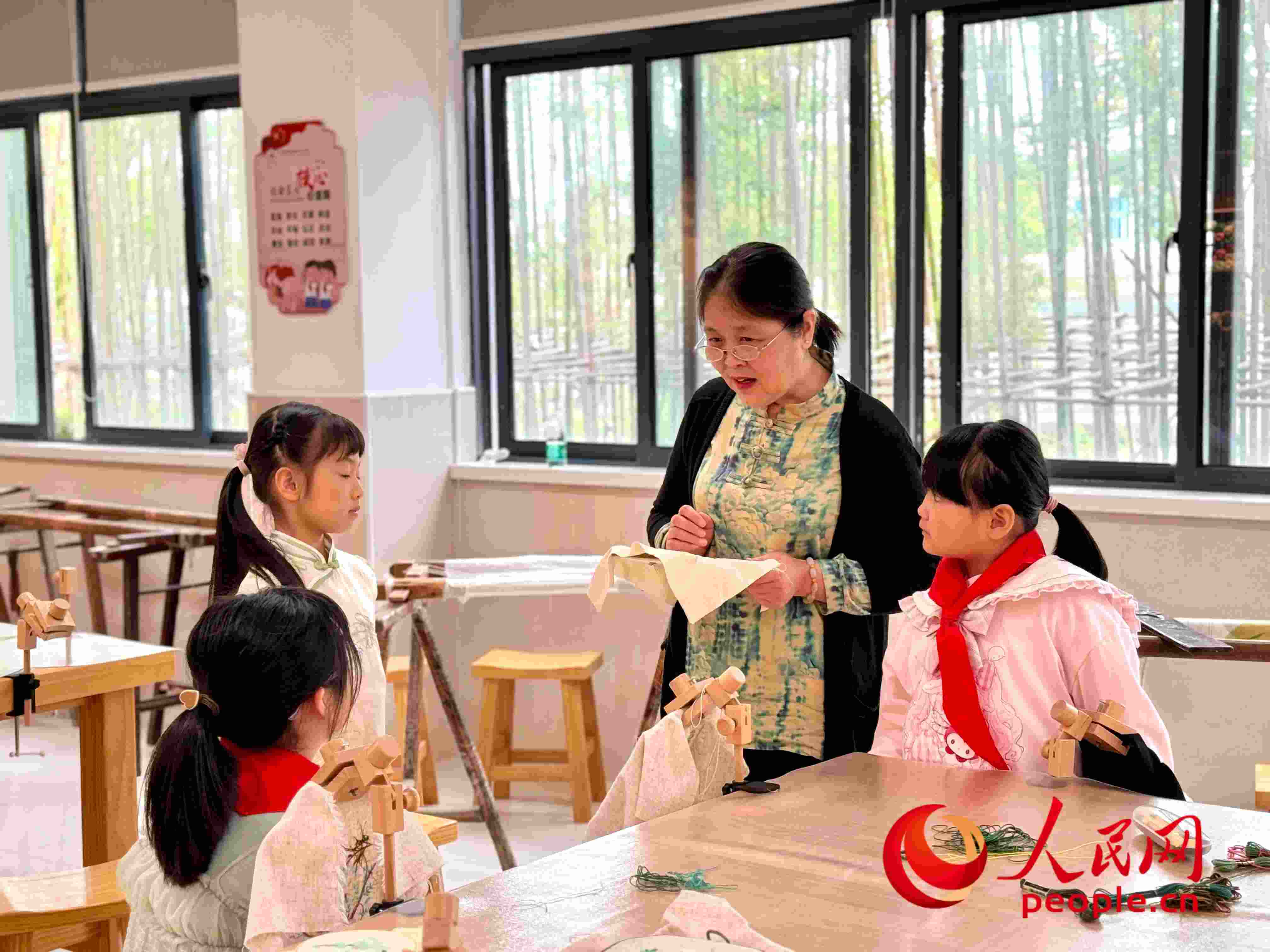顧建珍（左三）在教孩子們刺繡知識。人民網(wǎng) 周靜圓攝