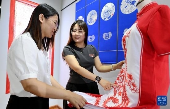 5月31日，在衡水市阜城縣一家剪紙工作室，游客在觀賞帶有剪紙元素的旗袍。
