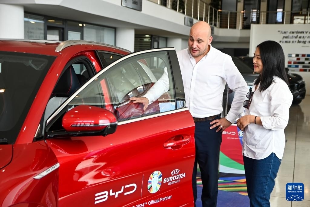 2024年5月29日，在馬耳他比爾基卡拉，馬耳他哈桑-扎米特汽車公司首席執(zhí)行官德古阿拉（左）介紹一輛比亞迪純電動(dòng)汽車。新華社發(fā)（喬納森·博格 攝）