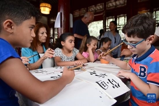 7月4日，在馬耳他桑塔露琪亞市的中國(guó)古典園林“靜園”，人們體驗(yàn)中國(guó)書(shū)法。新華社發(fā)（喬納森·博格 攝）