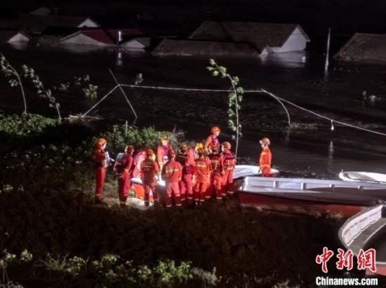  7月6日凌晨3時，在湖南岳陽華容縣團洲垸洞庭湖一線堤防，救援人員剛剛完成一次救援任務，遠處是被淹的民房。中新社記者 白祖偕 攝