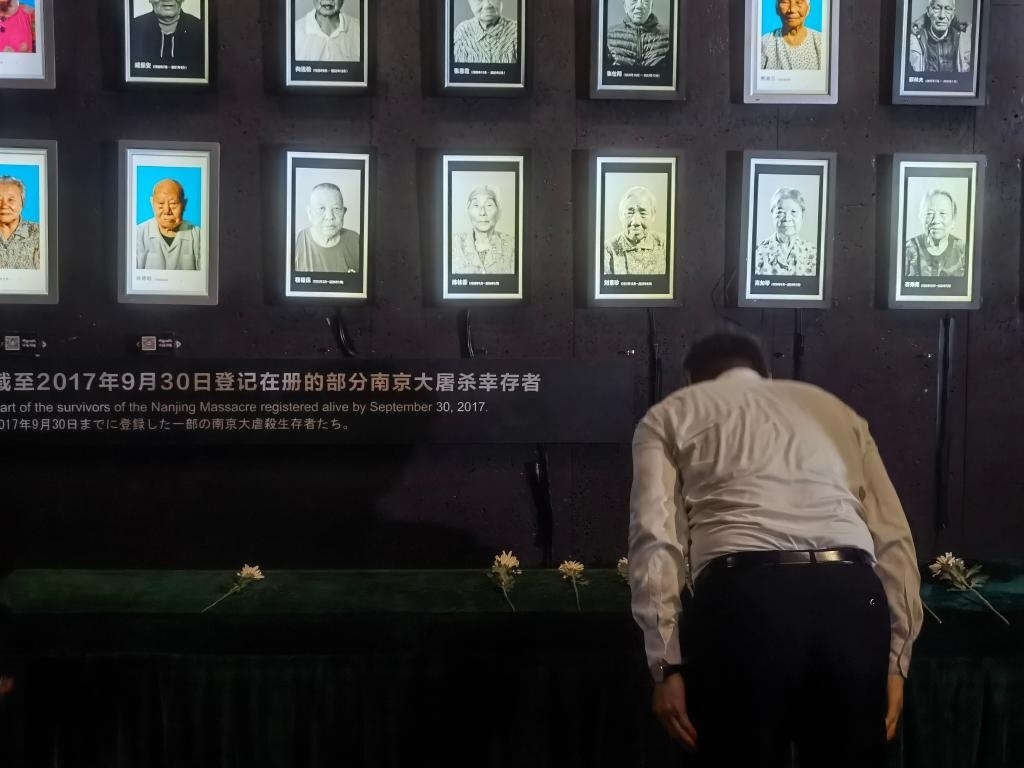 7月18日，人們向離世的南京大屠殺幸存者獻(xiàn)花、鞠躬。新華社記者邱冰清 攝