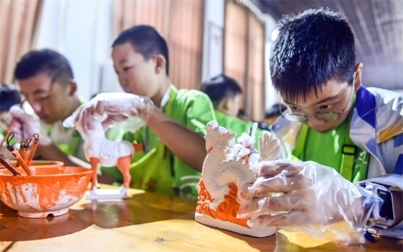小朋友們在洛陽市孟津區(qū)朝陽鎮(zhèn)南石山村體驗唐三彩素胎施釉技藝。圖片來源：視覺中國