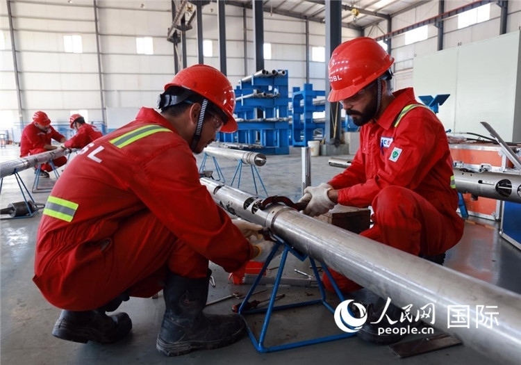 中伊員工共同在檢修鉆井設(shè)備。人民網(wǎng)記者管克江攝