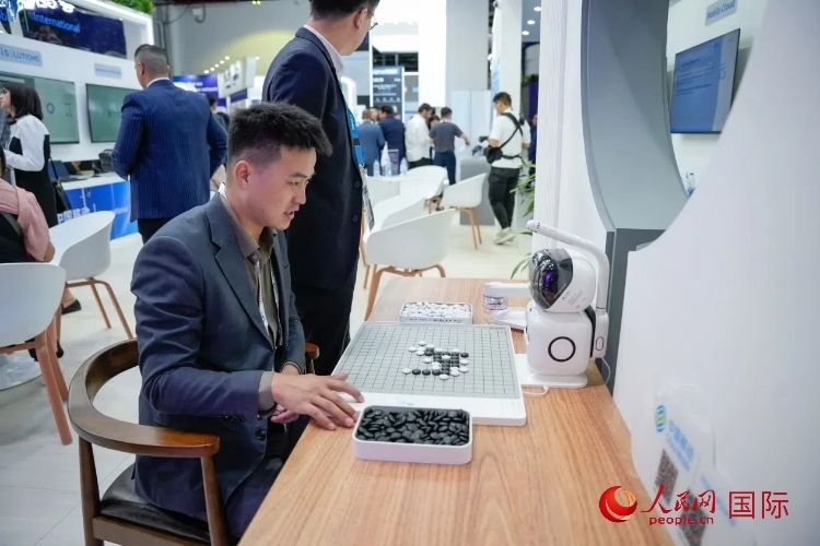 觀眾在中國(guó)移動(dòng)國(guó)際有限公司展臺(tái)體驗(yàn)智慧圍棋機(jī)器人。人民網(wǎng) 塔里克·易卜拉欣攝