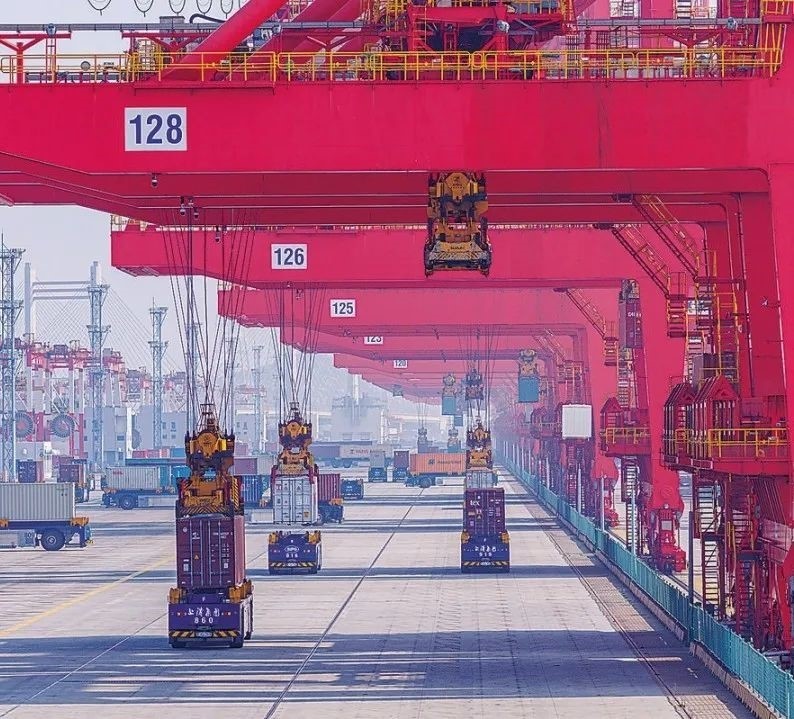 共建“一帶一路”國家在工作制度對接、技術標準協(xié)調、檢驗結果互認等方面強化合作、統(tǒng)一標準，貿(mào)易自由化便利化水平不斷提升。上海洋山港海關對接共建國家進出口貨物相關標準，推動通關一體化方式申報，提升通關效率。圖為無人駕駛的全自動導引車在洋山港穿梭往來，搬運集裝箱。王初 攝