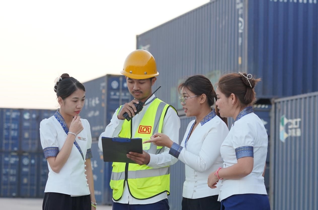 萬象南站貨運(yùn)值班員陳尼啦（左一）與同事在一起討論工作。老中鐵路有限公司供圖