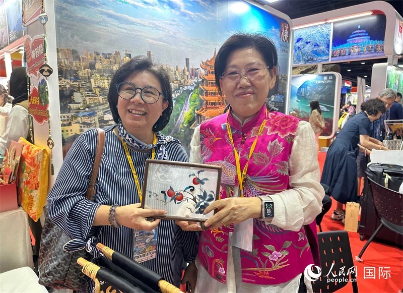 中國“大冶刺繡”傳承人劉小紅（右）參加泰國國際旅游展，向觀眾介紹中國非遺刺繡針法。人民網(wǎng)記者 簡(jiǎn)承淵攝