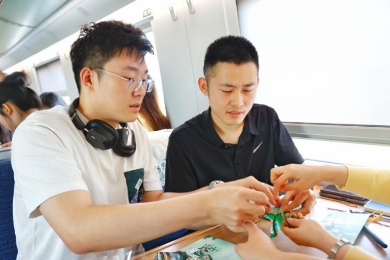 G232次旅客親手制作端午荷包和五彩繩。王磊攝