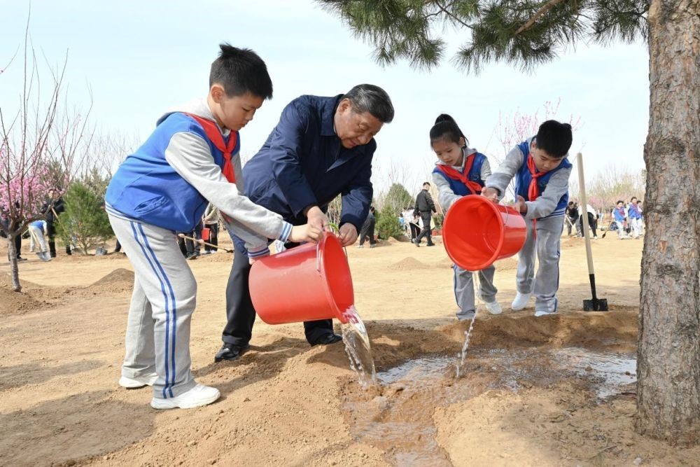 2025年4月3日，習(xí)近平總書記等來到北京市豐臺區(qū)永定河畔參加首都義務(wù)植樹活動。這是習(xí)近平總書記同少先隊(duì)員一起給剛栽下的樹苗澆水。新華社記者 謝環(huán)馳 攝